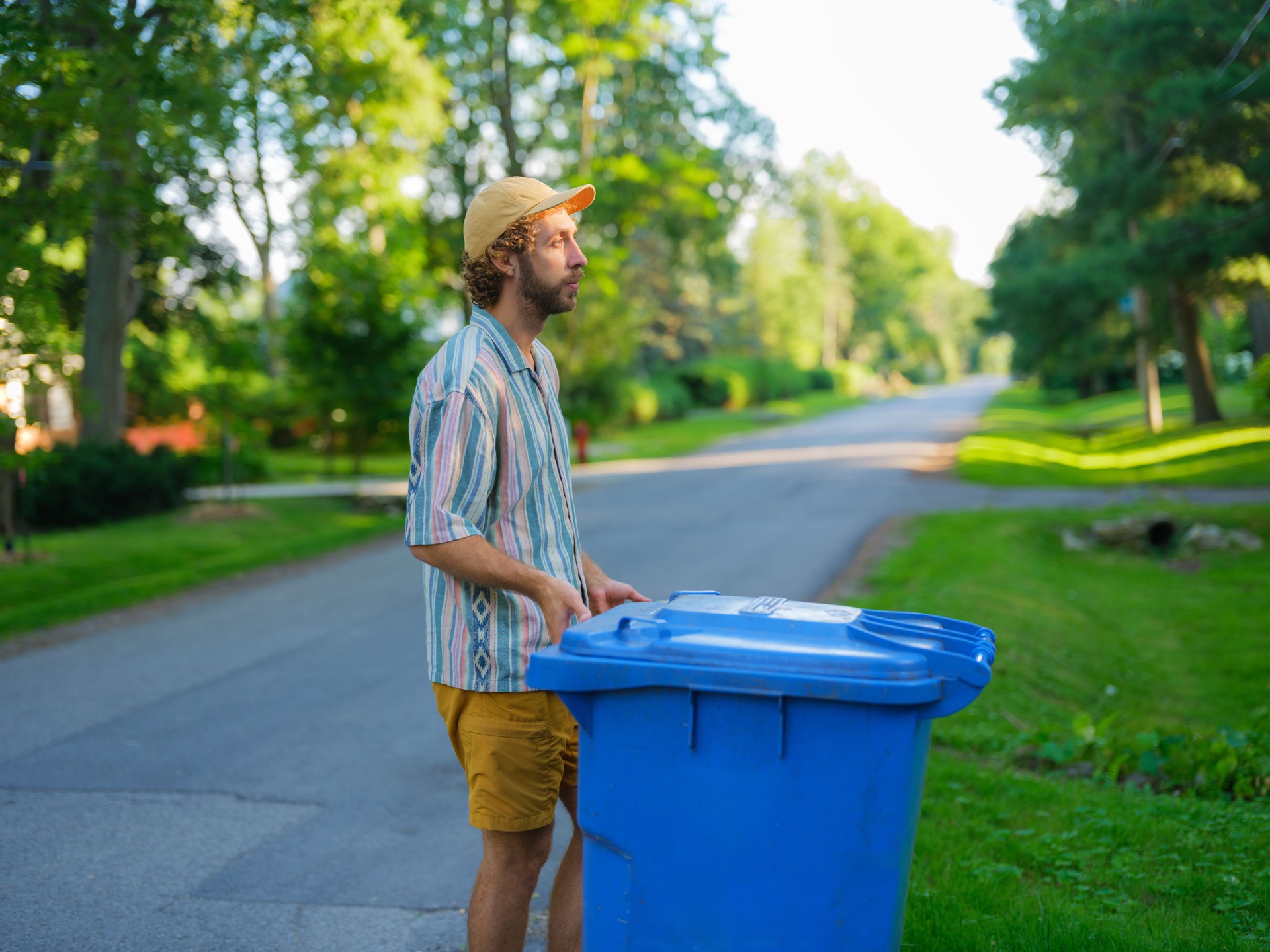 Man taking back his garbage bins on the front yard in suburbs